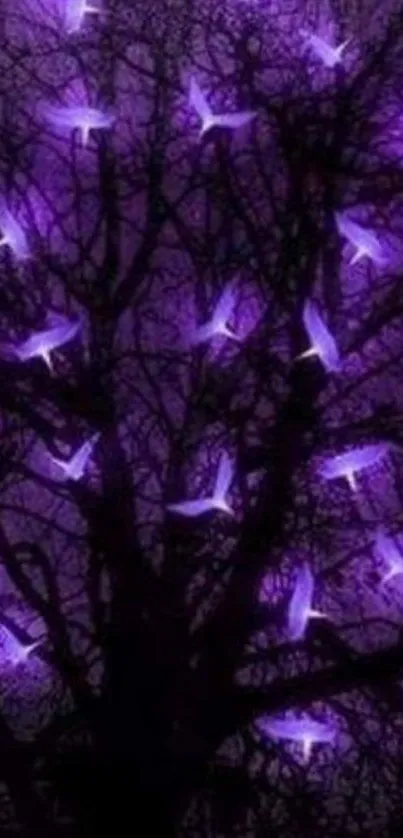 Silhouette of a tree with glowing purple birds at night.