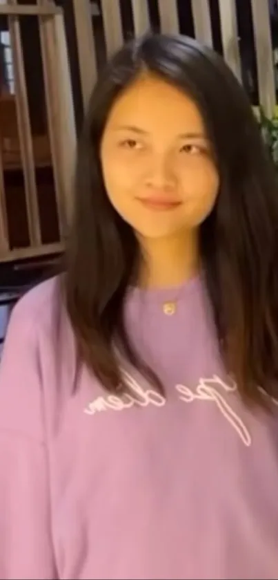 Young woman in a purple sweater standing indoors.