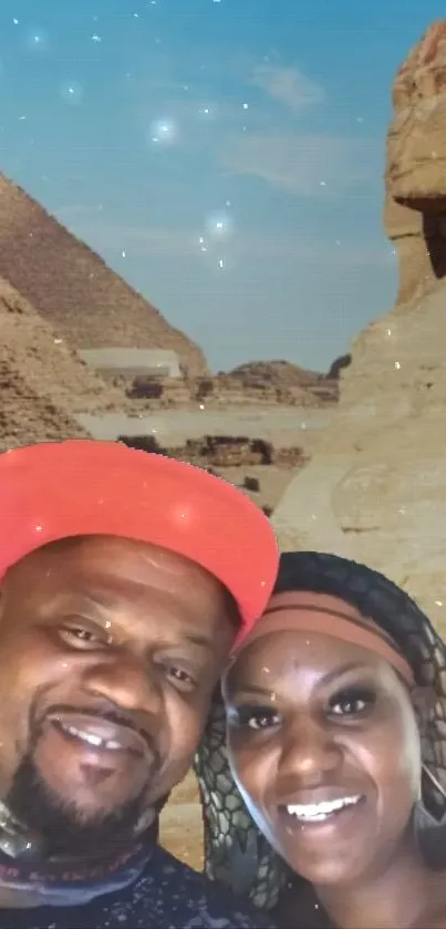 A couple smiling in front of Egyptian pyramids under a starry night sky.