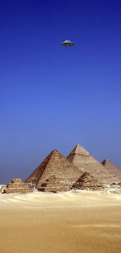 UFO hovering over pyramids in a blue sky.