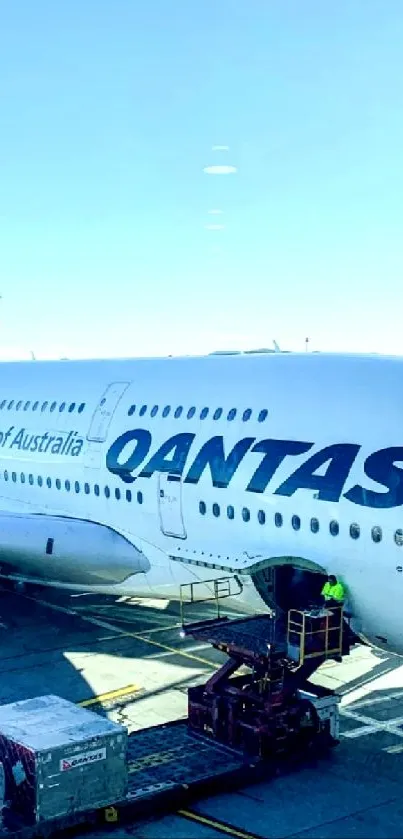 Qantas airplane on tarmac under clear sky, ready for boarding.