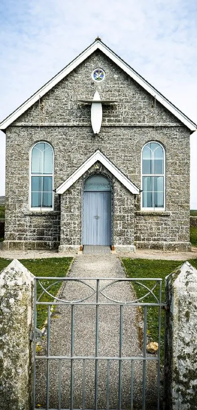 Quaint stone church with blue door and cloudy sky backdrop.