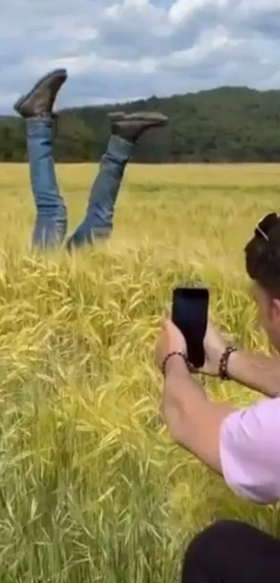 Man photographing legs in a wheat field.