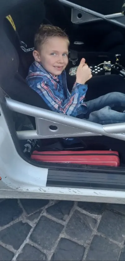 Child in a racing car seat, radiating joy.