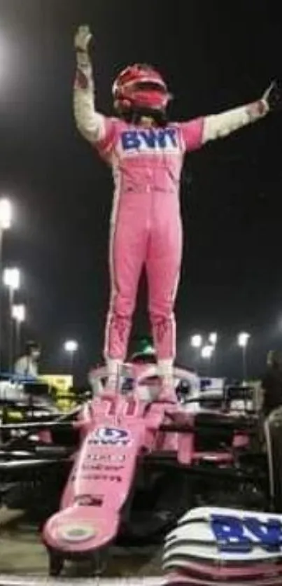 Race car driver celebrates victory at night on vehicle.