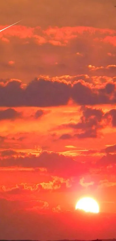 Vibrant red sunset with clouds and meteor across the sky.