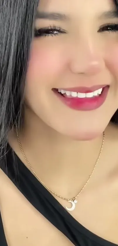 Woman smiling with a crescent moon necklace and black dress.