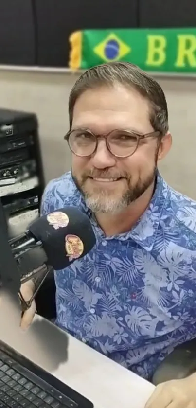 Radio host in studio with Brazilian flag backdrop.