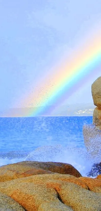 Vibrant rainbow arches over a rocky beach, touching a tranquil blue ocean.