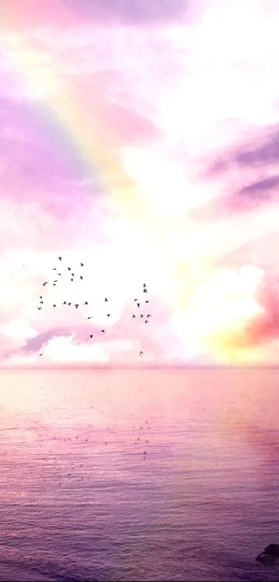 Rainbow over serene ocean with flying birds and pastel clouds at sunset.