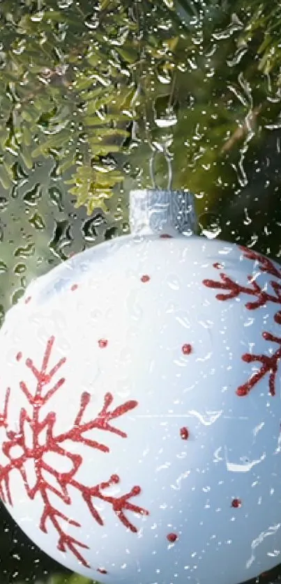 White Christmas ornament with red snowflakes behind raindrop-covered glass.