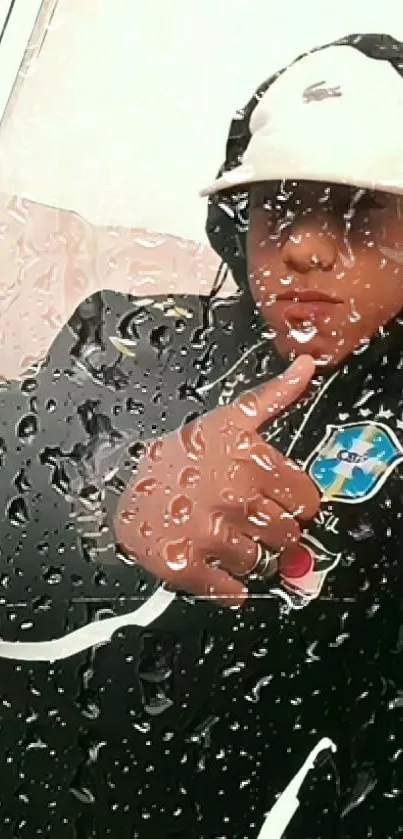 Portrait under glass with raindrops, featuring a figure in a hoodie and modern attire.