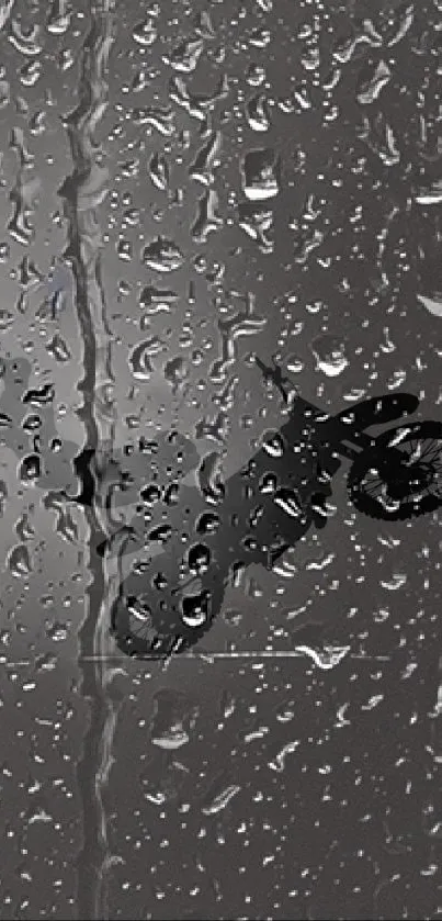 Motorcycle silhouette behind raindrops on glass in grayscale.