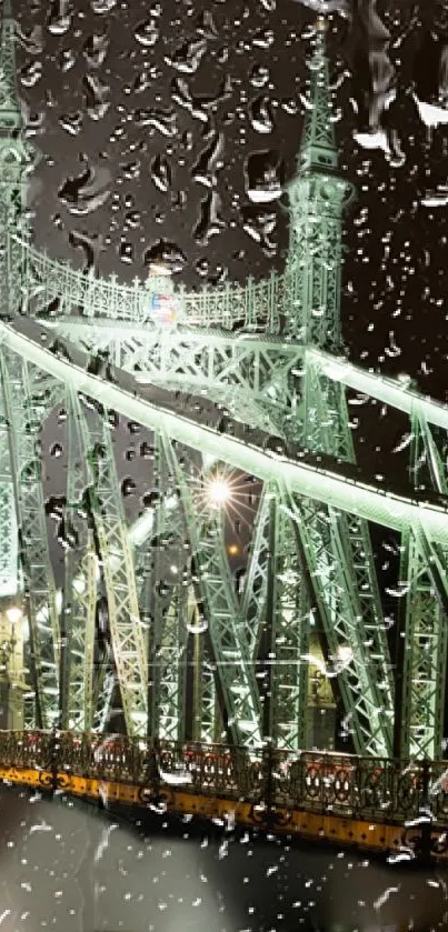 Rainy night view of an illuminated green bridge with raindrops in the foreground.