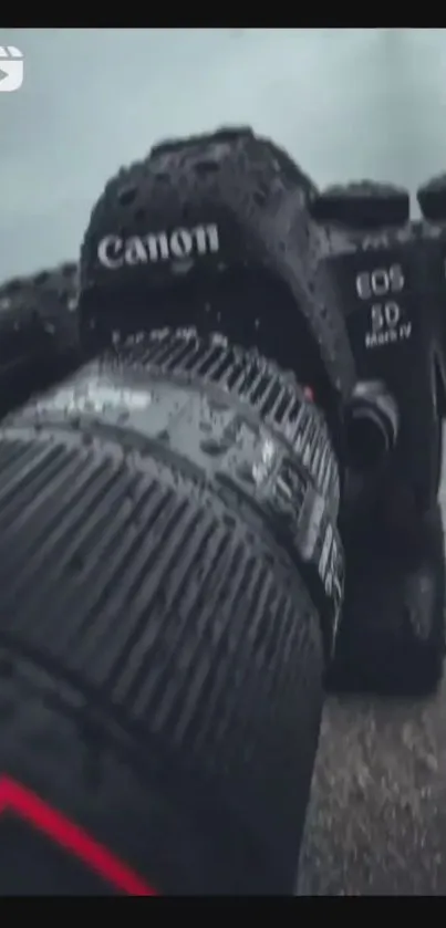 A close-up view of a Canon camera with raindrops on the lens.