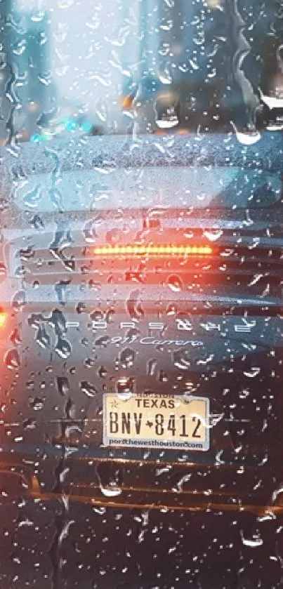 Car rear view with rain on window and taillights glowing at night.