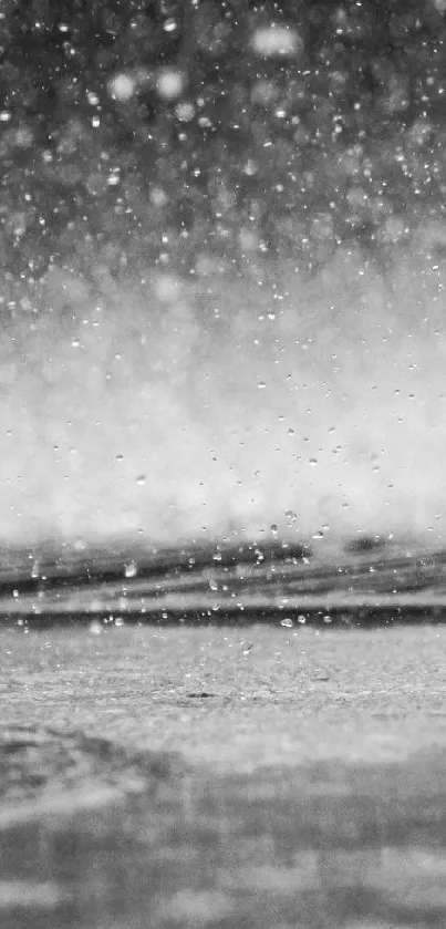 Black and white image of raindrops falling on a surface.