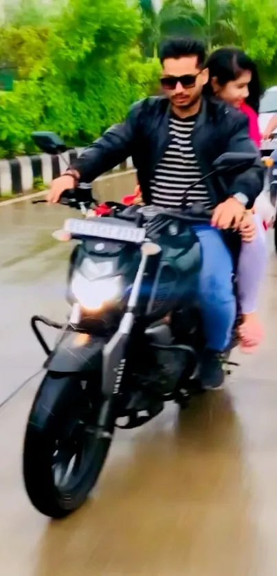 Couple riding a motorcycle on a wet urban street.