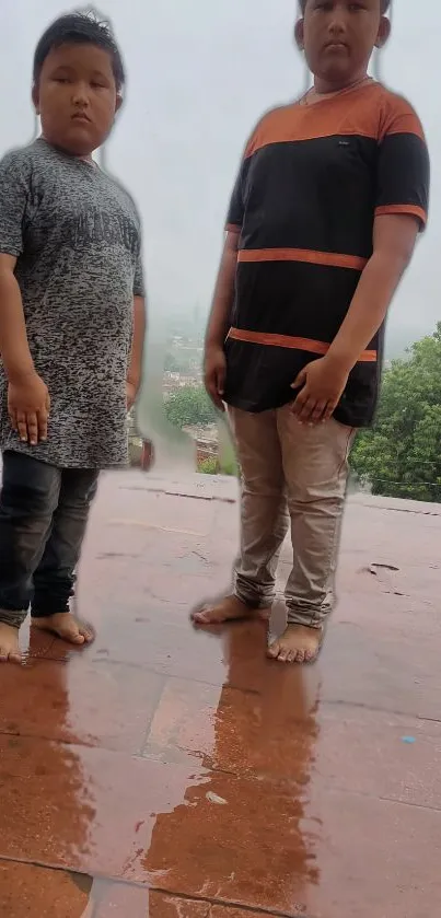 Two children standing in rain on terracotta tiles.