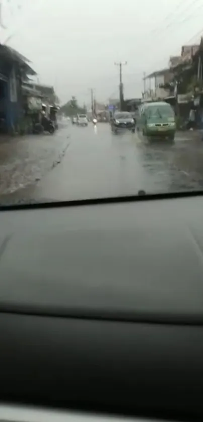 Rainy urban street view from a car window, showcasing a wet road.