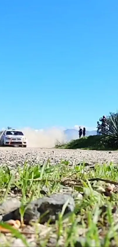 Rally car speeding on a scenic dirt road under a blue sky.