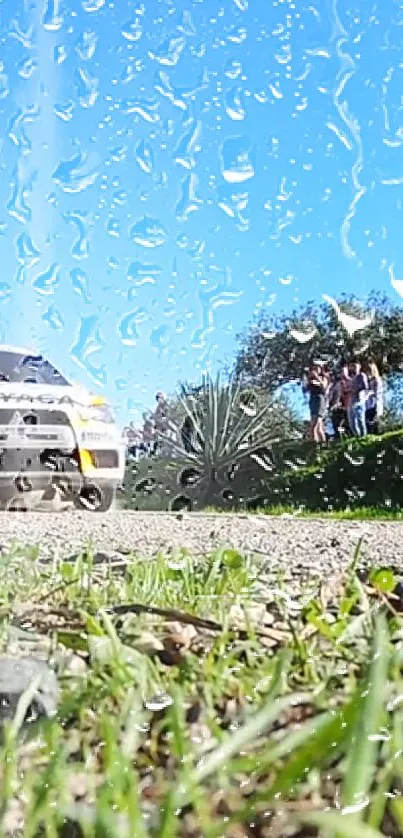 Rally car with raindrops on glass in front of a bright blue sky.