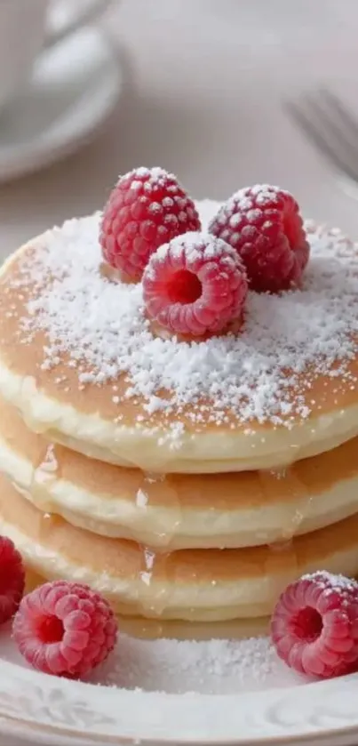 Fluffy pancakes topped with raspberries and sugar.