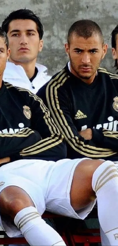 Real Madrid players in black jerseys on the bench, focused and ready.