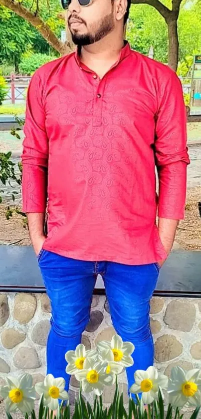 Man in red kurta and blue jeans with flowers in park.