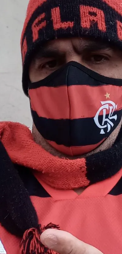 Fan dressed in red and black with a cap and scarf.