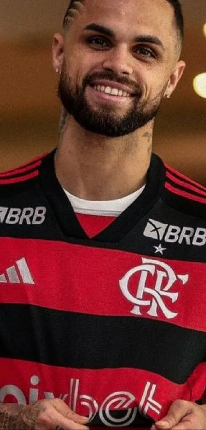 Man in red and black sports jersey smiling in vibrant background.