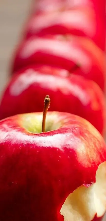 Close-up of a red apple with bite missing, on a wooden table.