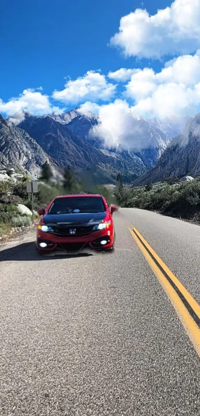 Red car driving on a mountain road under a blue sky.