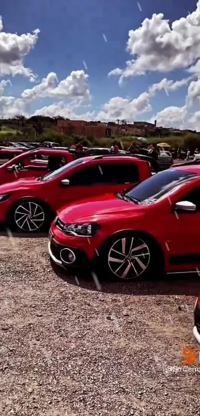 Bright red cars lined up under a clear blue sky at an outdoor event.