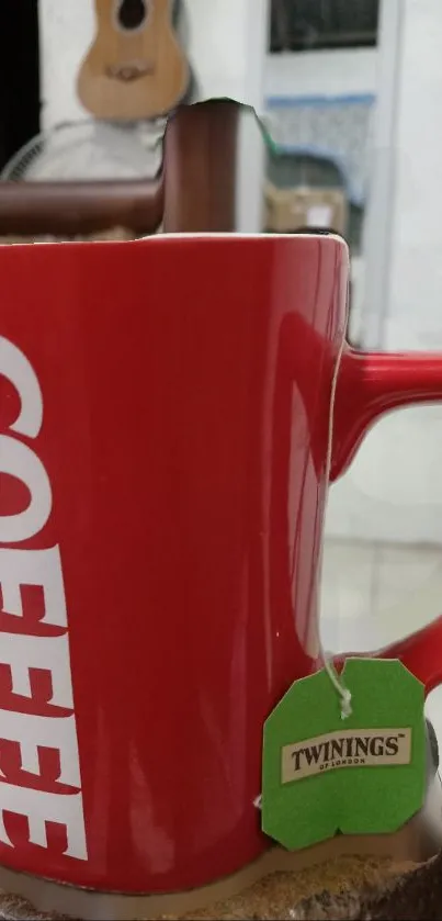 A vibrant red coffee mug with a green tea bag attached.