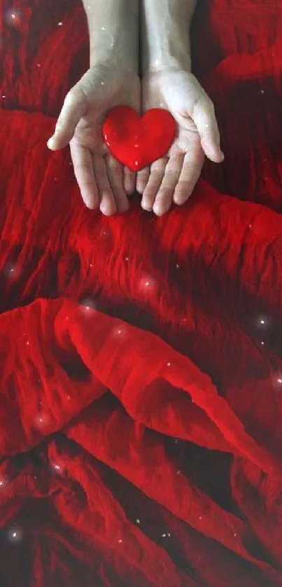 Red heart held in hands on vibrant red fabric background.