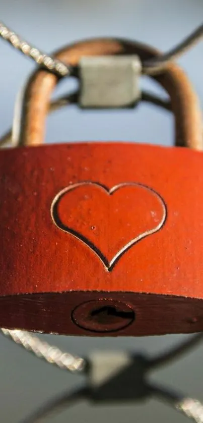 A red padlock with a heart symbol hanging on a fence.