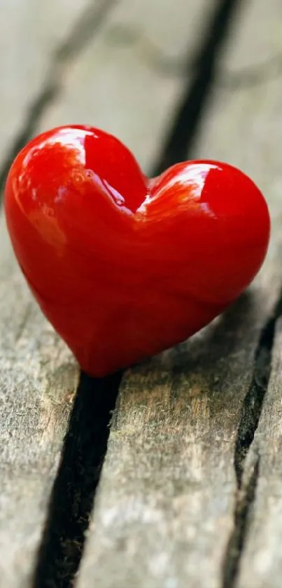 Vibrant red heart resting on rustic wooden surface.