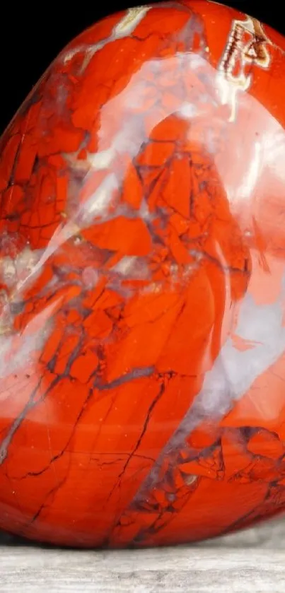 Red jasper heart stone on a textured surface.