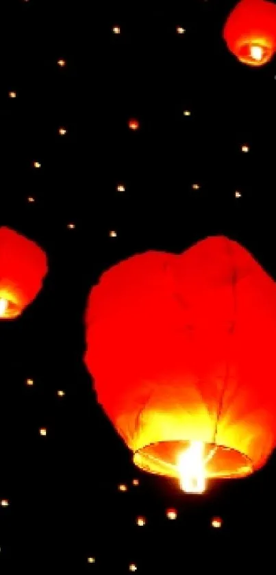 Floating red lanterns in night sky on a dark background, glowing brightly.