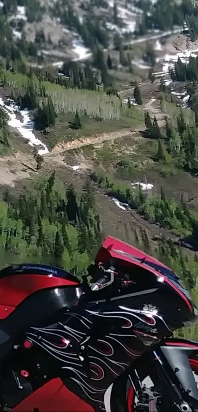 Red motorcycle with flames against green mountain backdrop.