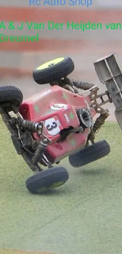 Red RC car performing a stunt on a green racetrack.