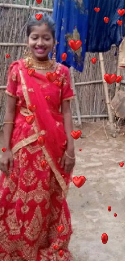 Woman in red saree with heart motifs on a mobile wallpaper.