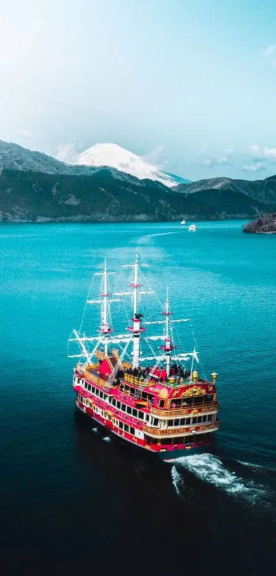 Majestic red ship sailing on turquoise waters with mountain backdrop.