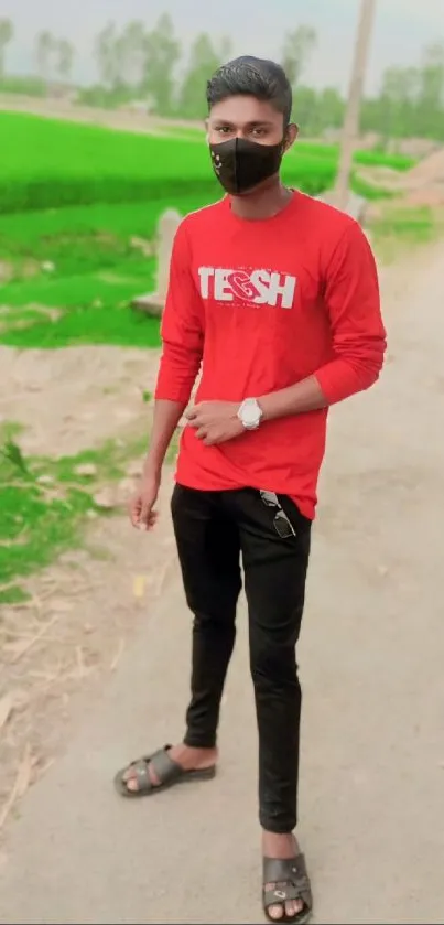 Man in red shirt with mask, standing on a rural path.