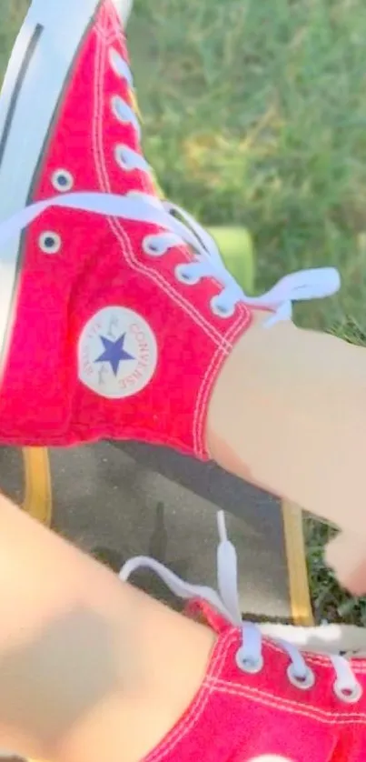 Red sneakers resting on a skateboard on grass.