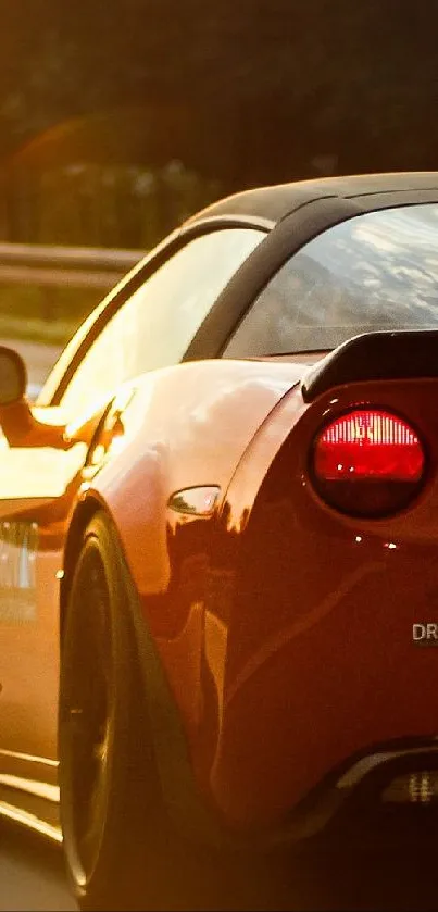 Red sports car driving at sunset on open highway.