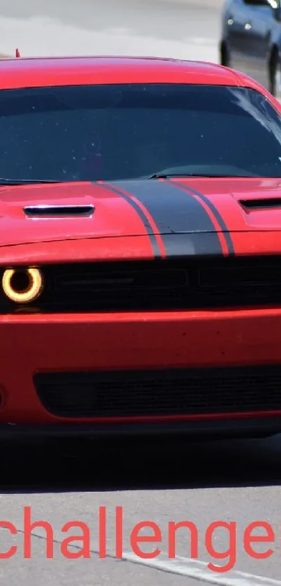 Red sports car with black stripes driving on a road.