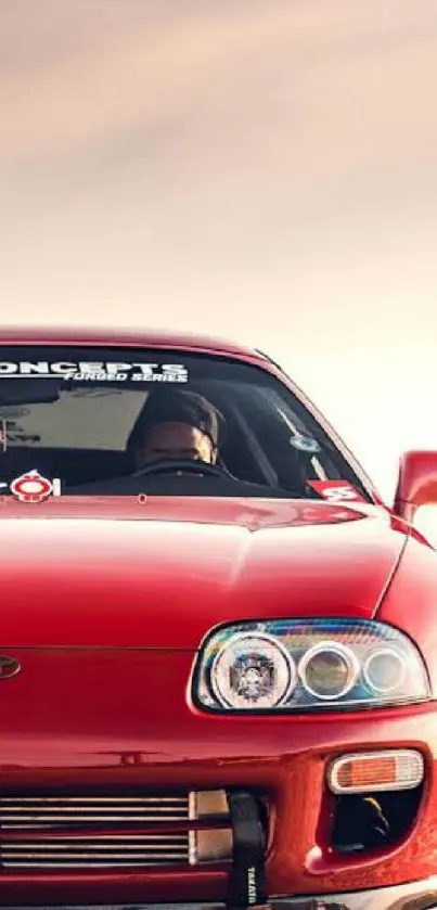 Front view of a red sports car against a sunrise.