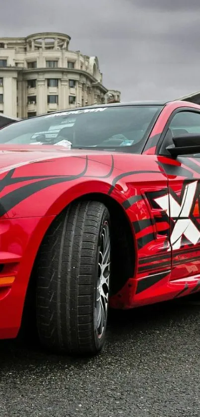 Red sports car with graphic design in urban setting.